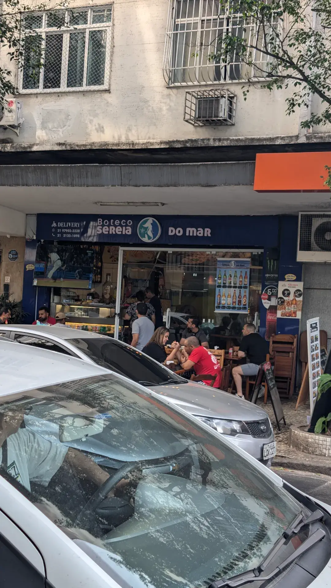 ブラジルの飲食店「Boteco Sereia do Mar」の外観です。人々の活気を感じる店舗の入り口と、周囲の街並みの様子です。