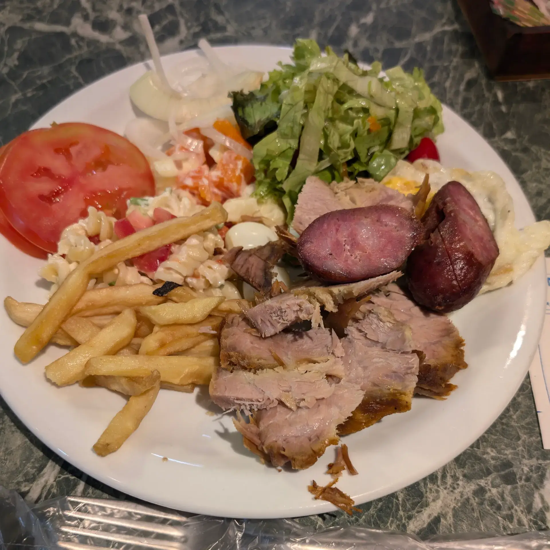 ブラジルの食堂でいただいたランチプレートのクローズアップです。ステーキやソーセージ、サラダなどが盛り付けられています。