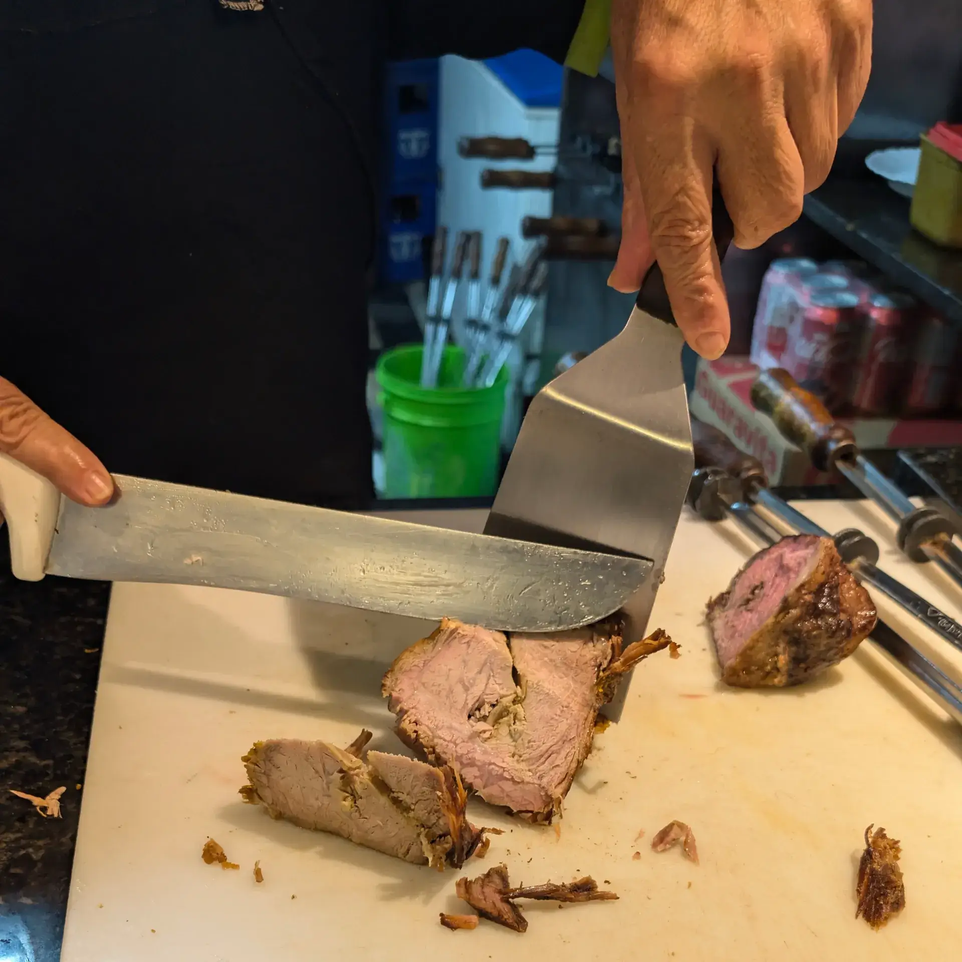 ブラジルの飲食店で、店員が大きな肉を切り分けて提供している様子です。