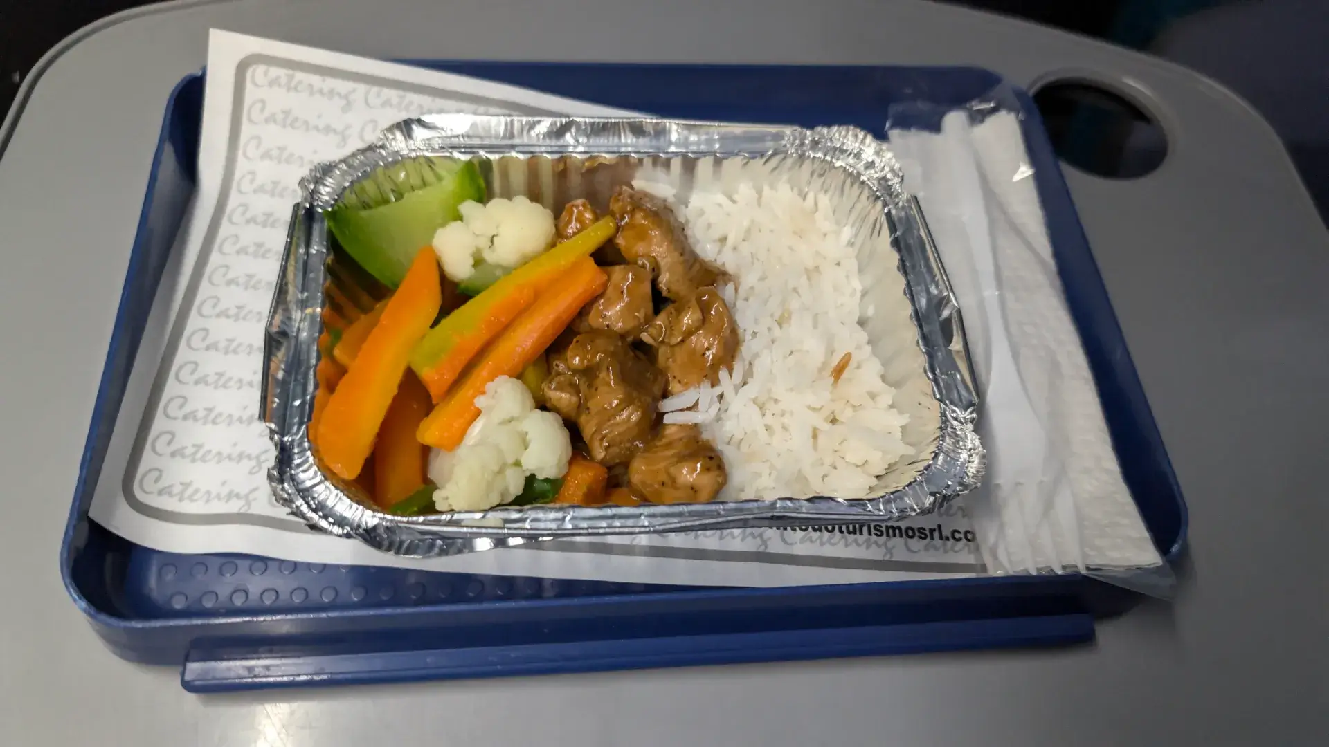 ウユニへの夜行バスの旅をさらに快適にする、温かい車内食のサービス。アルミ容器の中には、照りよく調理された鶏肉のソテー、鮮やかなニンジンやカリフラワーなどの蒸し野菜、そしてふっくらと炊かれた白米が美しく盛り付けられています。