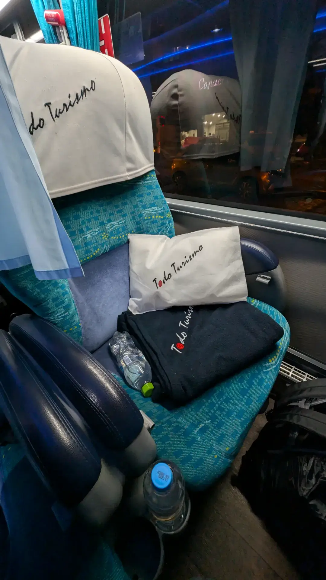 ラパスの喧騒を離れ、鏡張りの絶景を求めてウユニへとひた走る夜行バス「Todo Turismo」。清潔感のある青いシートには、専用の枕とブランケットが用意され、足元にはミネラルウォーターが完備されるなど、長距離移動を感じさせない至れり尽くせりのホスピタリティが光ります。窓の外にはラパスの夜景が遠ざかり、静まり返った車内にはこれからの冒険への期待と心地よい緊張感が漂います。明朝、目覚めた瞬間に広がるであろう白い大地を夢見ながら、アンデスの夜を越えていく特別な移動の記録です。