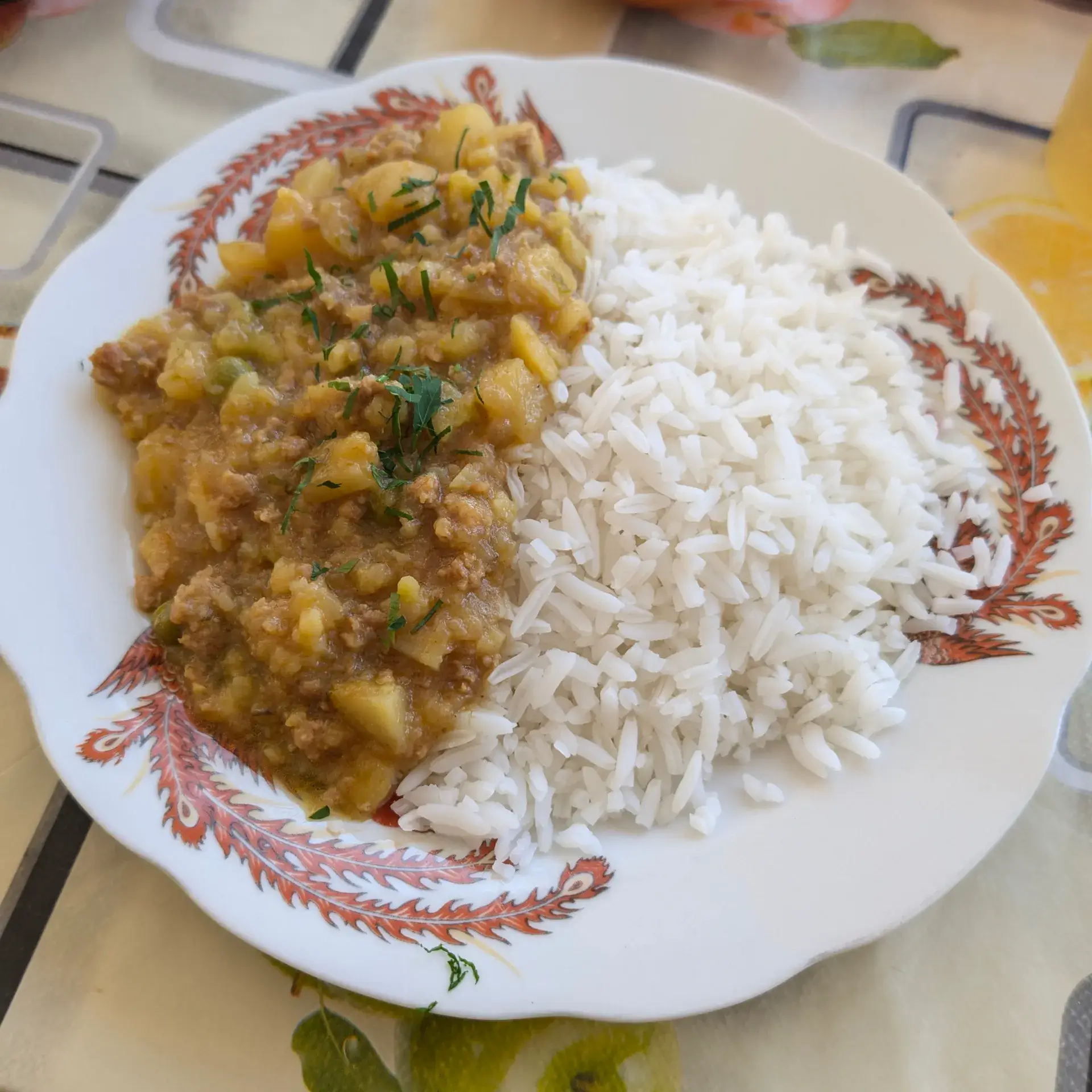 ラパスの食堂で楽しむ、ボリューム満点のボリビア風煮込み料理。ホクホクとしたジャガイモと挽肉（または細かく裂いたお肉）を、アヒ（唐辛子）の風味が効いたソースでじっくり煮込み、山盛りの白いご飯に添えられています。上に散らされた新鮮なパセリが彩りと香りのアクセント。