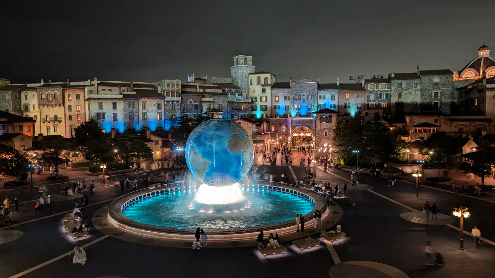 東京ディズニーシーのエントランスにある「ディズニーシー・アクアスフィア」の夜景。長時間露光により噴水の水流が白く輝き、背後にはライトアップされた東京ディズニーシー・ホテル・ミラコスタの異国情緒あふれる建物が広がる幻想的な風景。