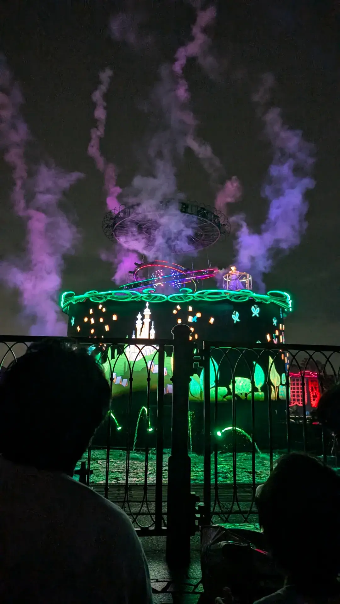 夜のメディテレーニアンハーバーで繰り広げられるショー「ビリーヴ！〜シー・オブ・ドリームス〜」の一場面。ラプンツェルの世界観を象徴する無数のランタンがプロジェクションマッピングで映し出され、紫色のスモークと鮮やかなグリーンの光が水面を彩る幻想的な光景。