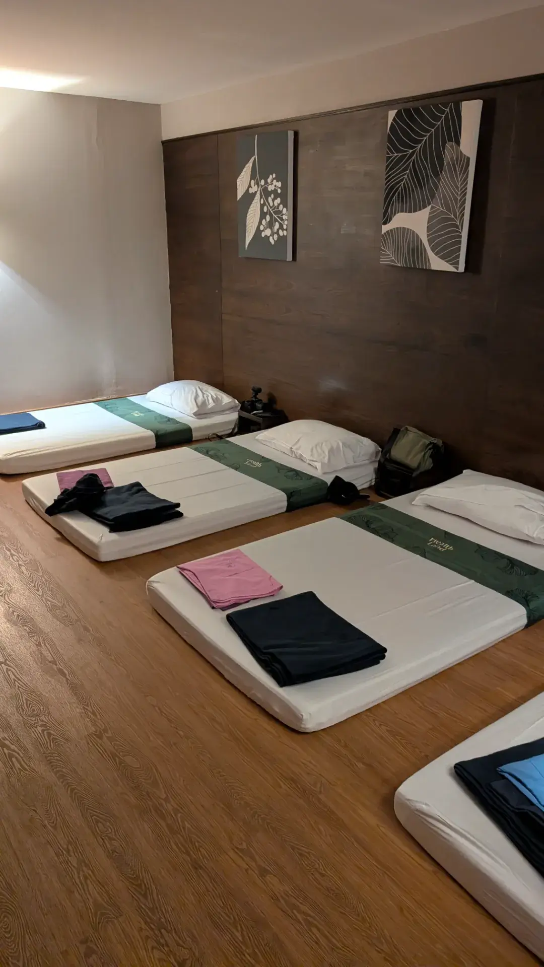 「ヘルスランド・スパ・アソーク」内にある、広々としたプライベート・マッサージルーム。清潔なシーツが敷かれたマットが並び、家族や友人同士でリラックスしながら同時に施術を受けられるよう配慮されています。落ち着いた木目調の壁と柔らかな照明、そして用意された清潔な着替え。都会の喧騒を忘れ、旅の疲れを心ゆくまで解き放つための、静寂に満ちた上質な空間です。