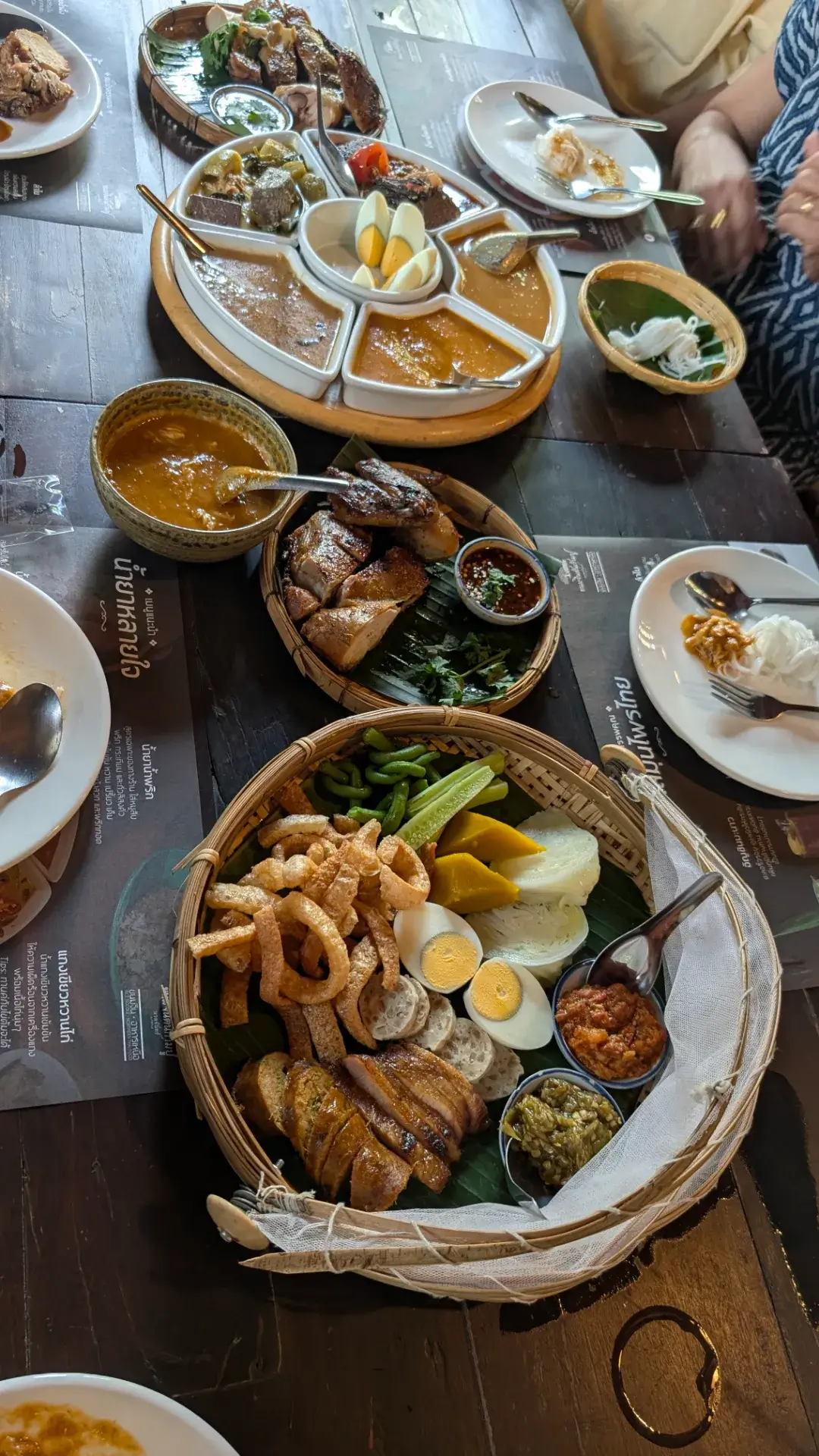 タイ北部・スコータイ地方の伝統的な料理セット。 カントークのような竹籠に盛り付けられたサイウア（チェンマイソーセージ）やケップムー（豚皮の揚げ物）、数種類のナムプリック（ディップ）など、彩り豊かな郷土料理が並ぶ豪華なランチテーブルです。