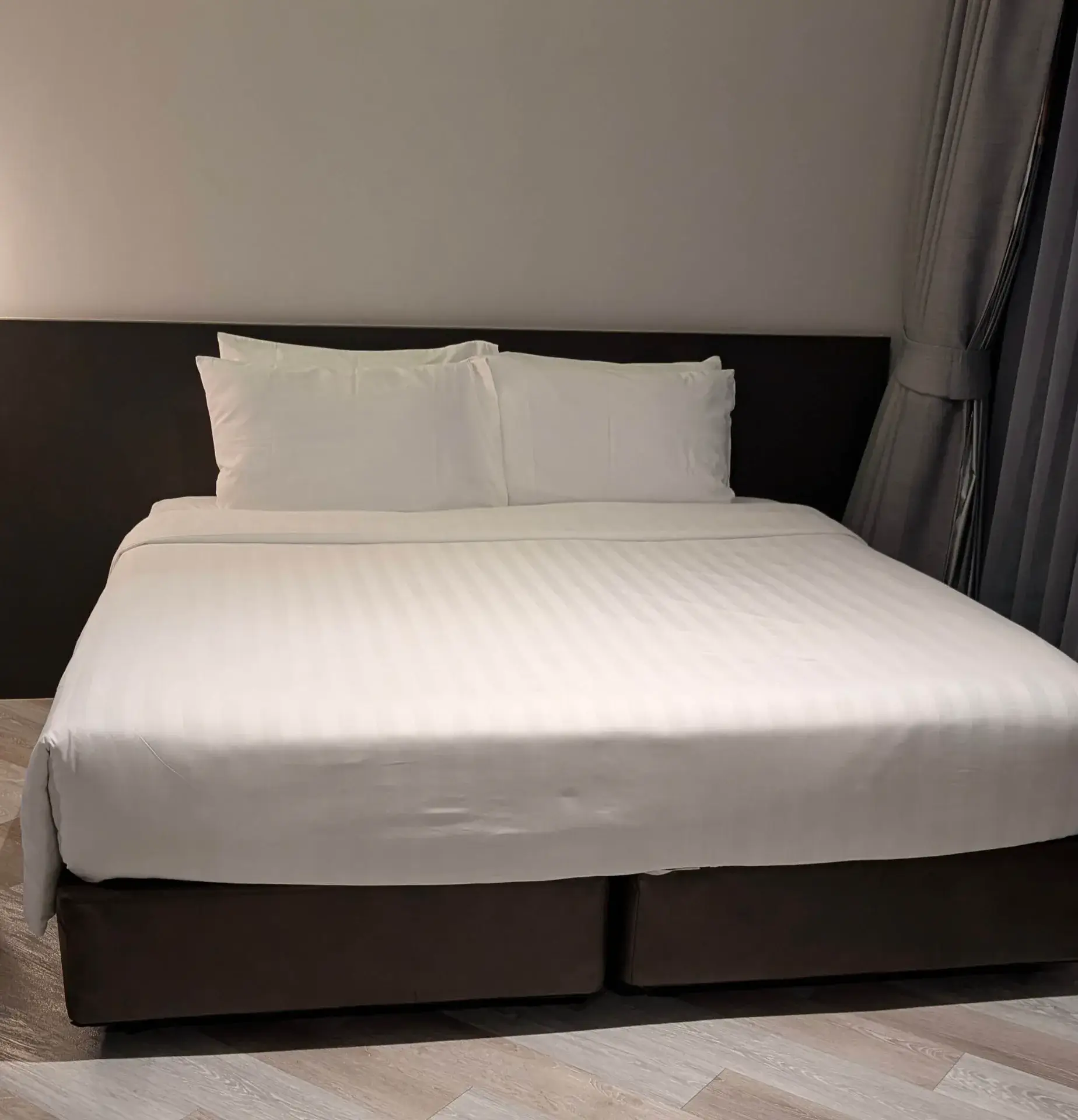 タイ旅行で宿泊したホテルの客室。広々としたキングサイズのベッドと清潔な白いリネンが、旅の疲れを優しく癒やしてくれます。シンプルでモダンなインテリアが落ち着いた空間を演出する、快適な滞在先の一コマです。