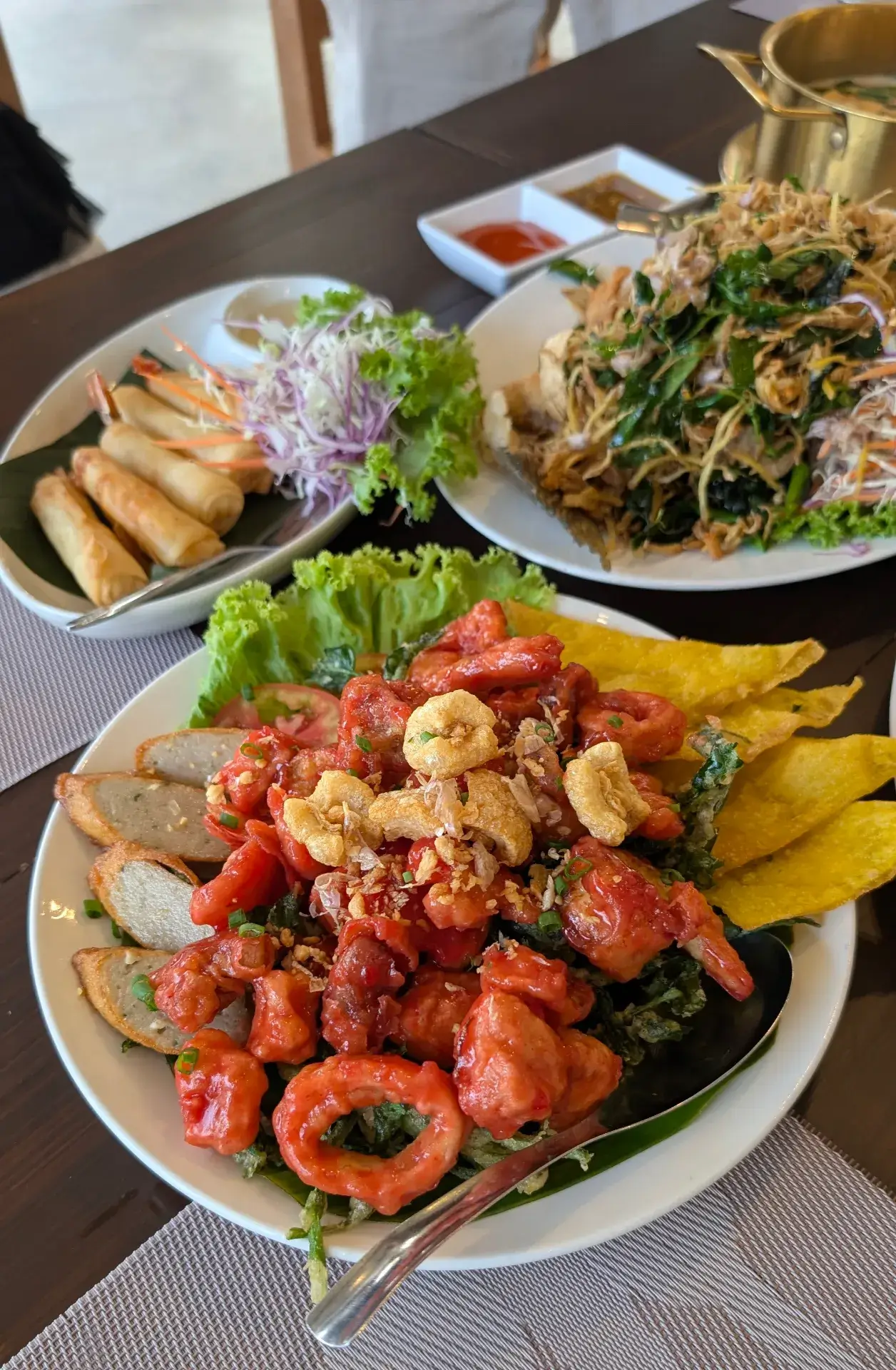 スコータイのレストランでの豪華な夕食。手前には赤いソースが絡んだ揚げ物や魚のすり身、奥には春巻きやハーブたっぷりの魚料理が並び、タイ料理らしい色彩豊かな盛り付けが食欲をそそる。