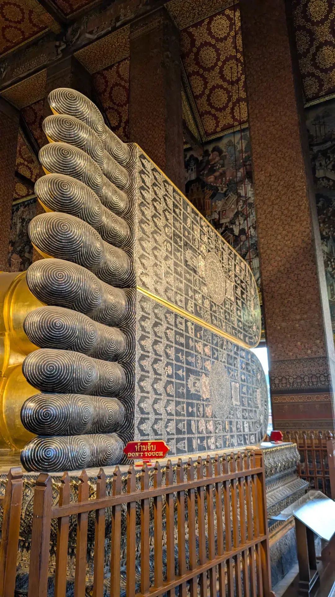 ワット・ポーの寝釈迦仏の足の裏。黒漆の上に、真珠貝を削り取った螺鈿（らでん）細工によって、仏教の世界観を象徴する108の図が精緻に描かれています。渦巻状の紋様が施された指先や、中央に配された法輪など、その芸術的な美しさは圧巻です。タイの精神的な伝統と高度な職人技が融合した、参拝の際に必ず注目したい重要な意匠です。