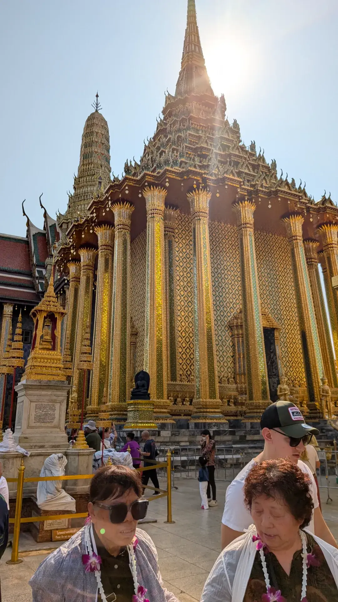 ワット・プラケオの境内にそびえ立つ、スリランカ様式の黄金の仏塔「プラ・シー・ラタナ・チェディ」。その隣には、仏教の聖典を納める精緻な装飾の経蔵（モンドップ）が並び、タイ王室寺院の圧倒的なスケールと美しさを象徴しています。逆光の中に輝く黄金のシルエットと、色鮮やかなタイル装飾が施された柱のコントラストが、訪れる人々を魅了する絶景のフォトスポットです。