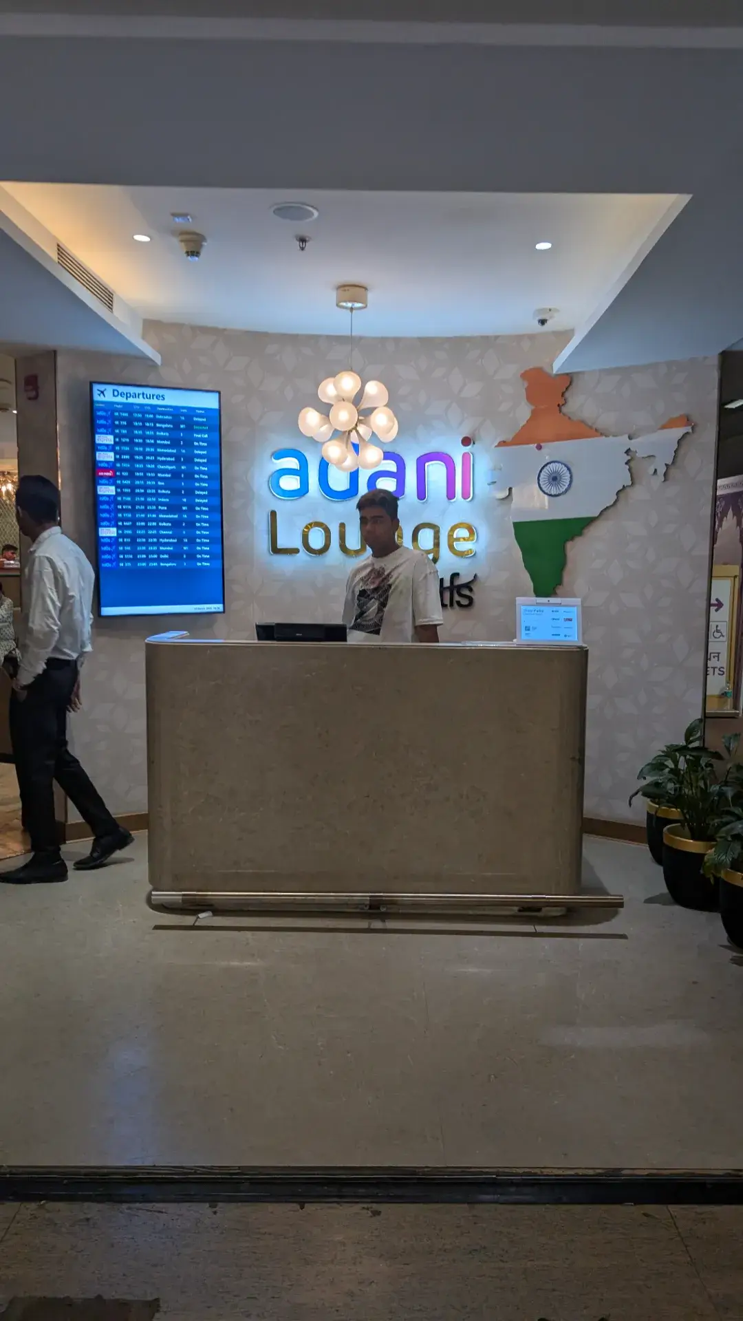 空港内にある「Adani Lounge」の受付カウンターと出発案内掲示板。