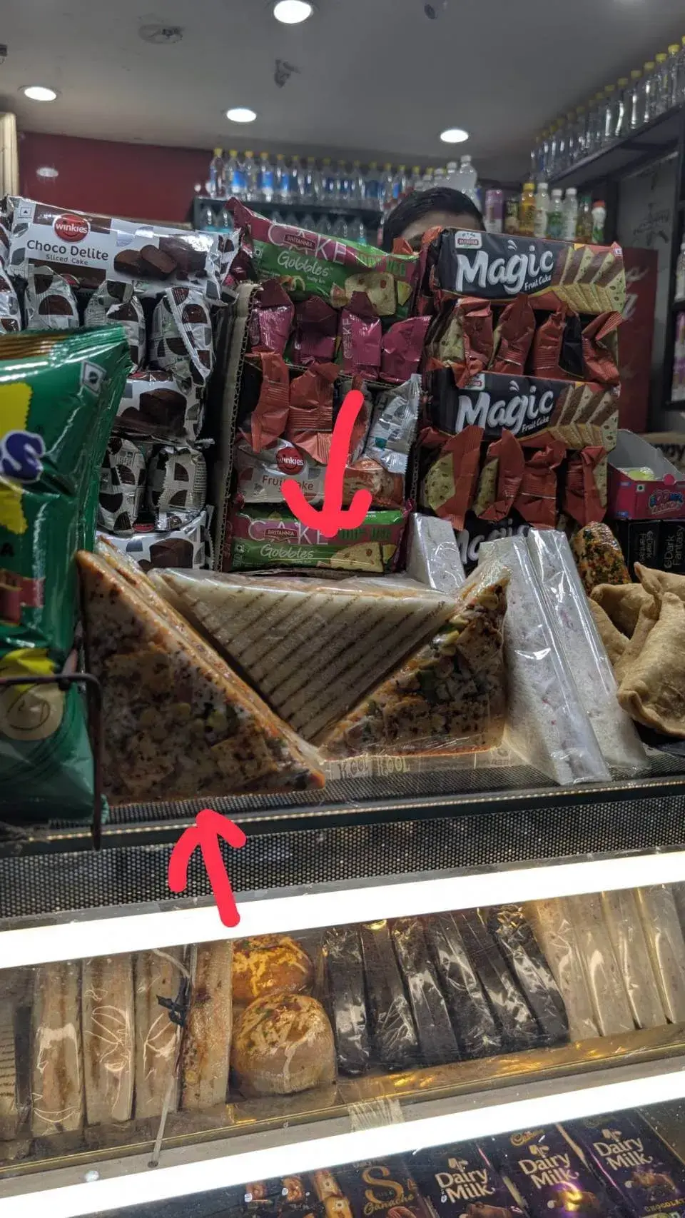 パン屋のショーケースに並ぶ黄色いパッケージのクッキーと、パック詰めされたホットサンドイッチ