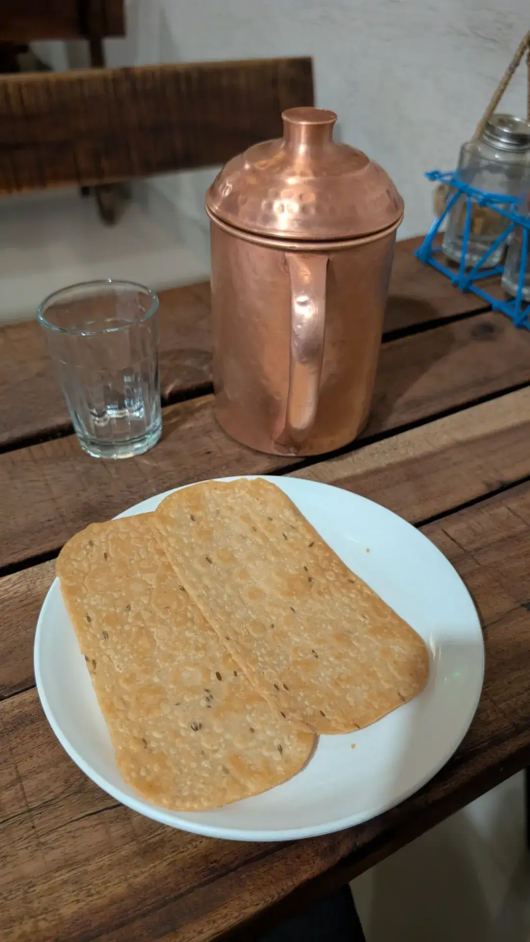 銅製の水差しとパパドが置かれたテーブルの様子