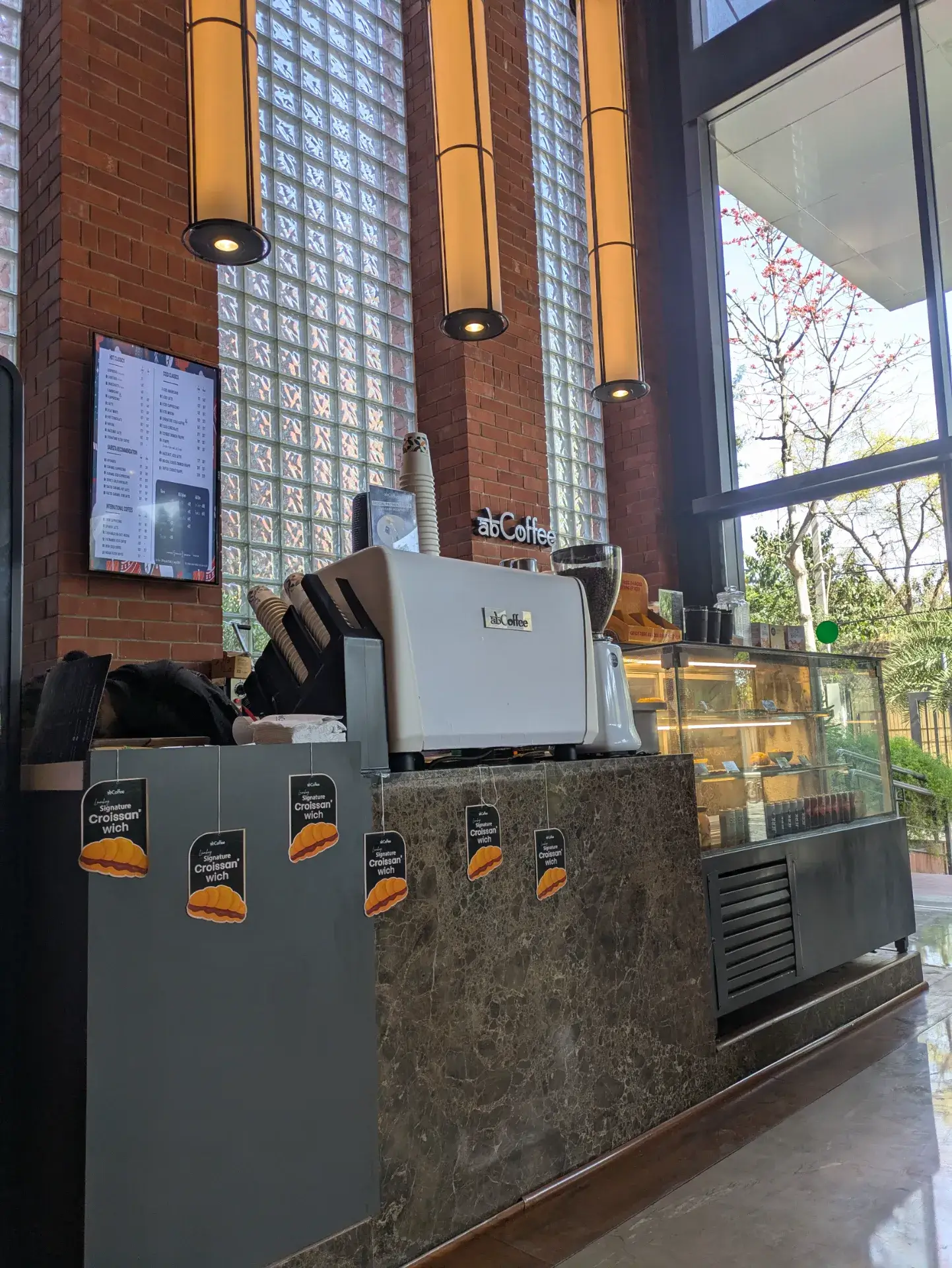 デリーの「abCoffee Max House Okhla」の店内。レンガ造りの壁とガラスブロック、洗練されたエスプレッソマシンが並ぶモダンなカウンター