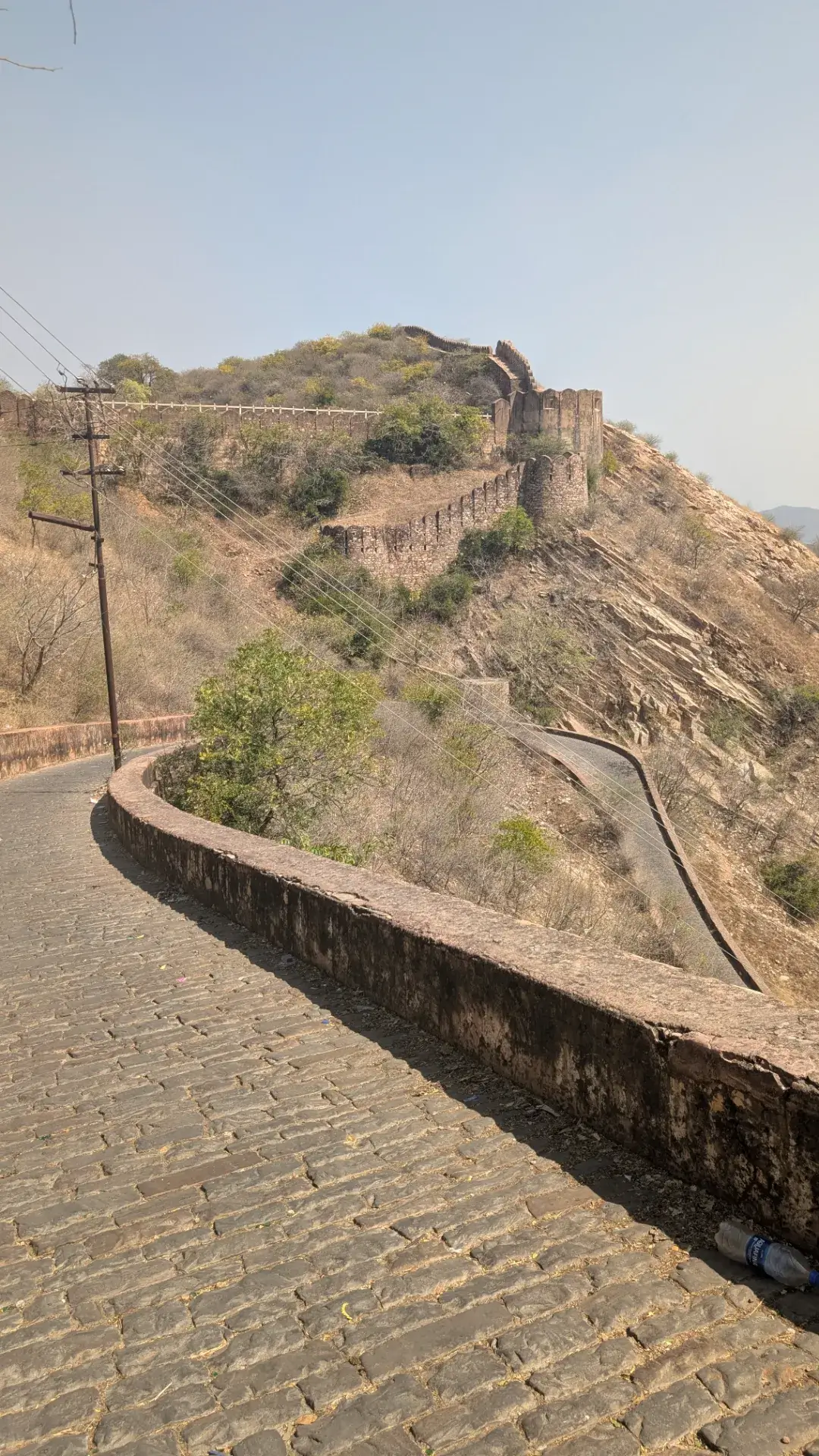 アンベール城周辺の丘の上に続く古い石造りの城壁と、山沿いに曲がりくねった石畳の道。