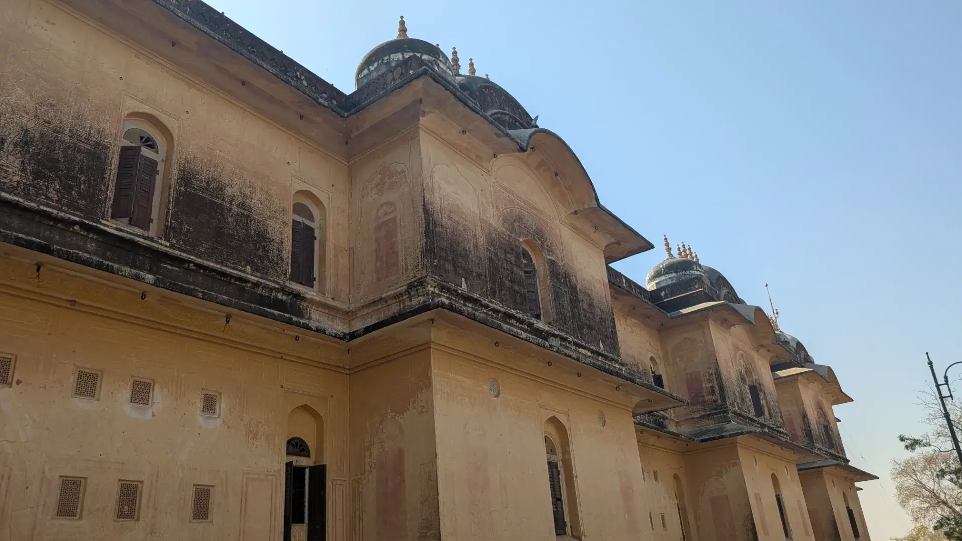 ジャイプールの歴史的な宮殿の建物。砂岩の壁面と伝統的なドーム屋根、窓のデザインが特徴。