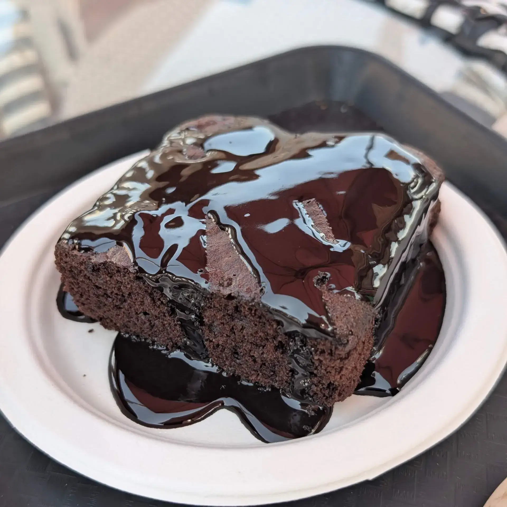 ジャイプールのカフェで提供されたデザート。白い紙皿に盛られた大きなチョコレートブラウニーに、光沢のある濃厚なチョコレートソースがたっぷりとかけられている様子。