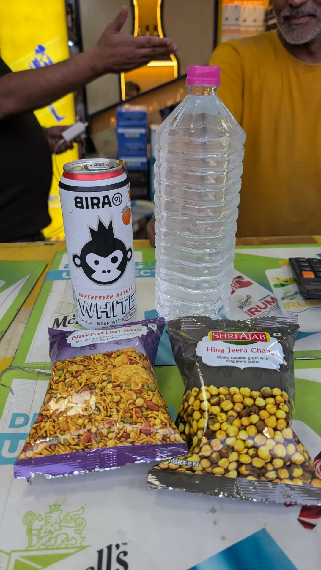 ビラ（Bira 91）ホワイトビール、ミネラルウォーター、インドの伝統的なスナック菓子（ナヴラッタンミックス、ヒング・ジーラ・チャナ）がテーブルに並べられている様子。