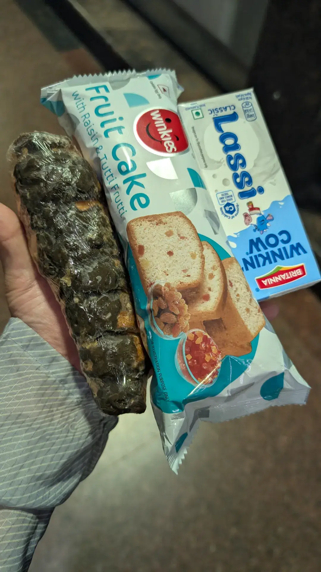 インドで手軽に購入できるフルーツケーキ、ラッシー、ラップで包まれた軽食のセット