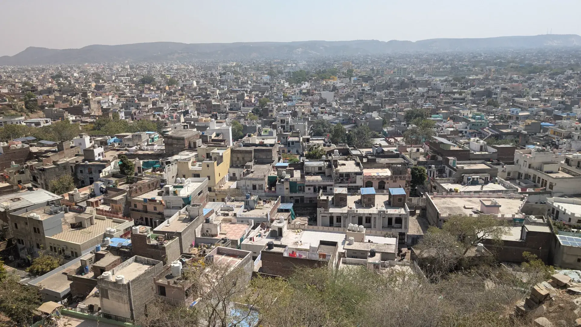 ジャイプールの街並みを見下ろすパノラマビュー。密集した住宅の屋根と遠くの山々。