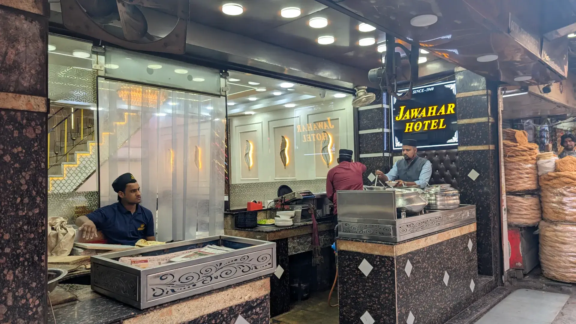 1940年創業の老舗「ジャワハル・ホテル」の外観と活気ある店内の様子