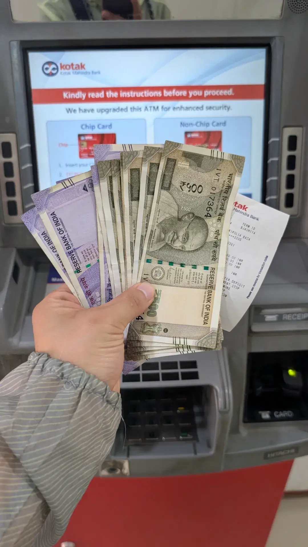 コタック・マヒンドラ銀行（Kotak Mahindra Bank）のATMで、引き出したばかりの500ルピー紙幣と利用明細を手に持っている様子。