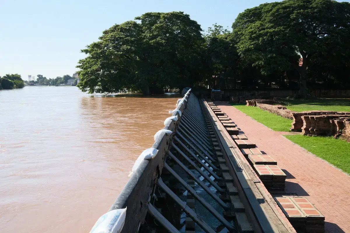 アユタヤ歴史公園の遺跡を、増水したチャオプラヤー川から守るための洪水防護壁(土嚢と鉄製の支え)です。タイ、水害対策、川沿い。