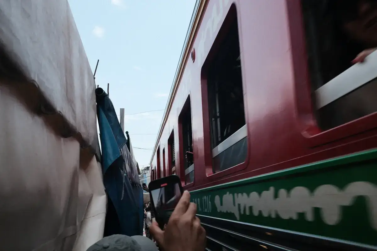 メークロン鉄道市場で、列車の車体が商店の日除け（オーニング）のすぐ脇を通り抜ける決定的な瞬間