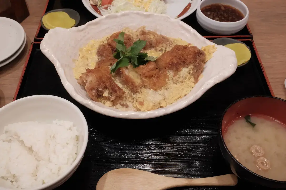 鳥良商店のチキンカツ煮定食。卵で閉じられたチキンカツ、白米、味噌汁、たくあん、おろしポン酢のセット。