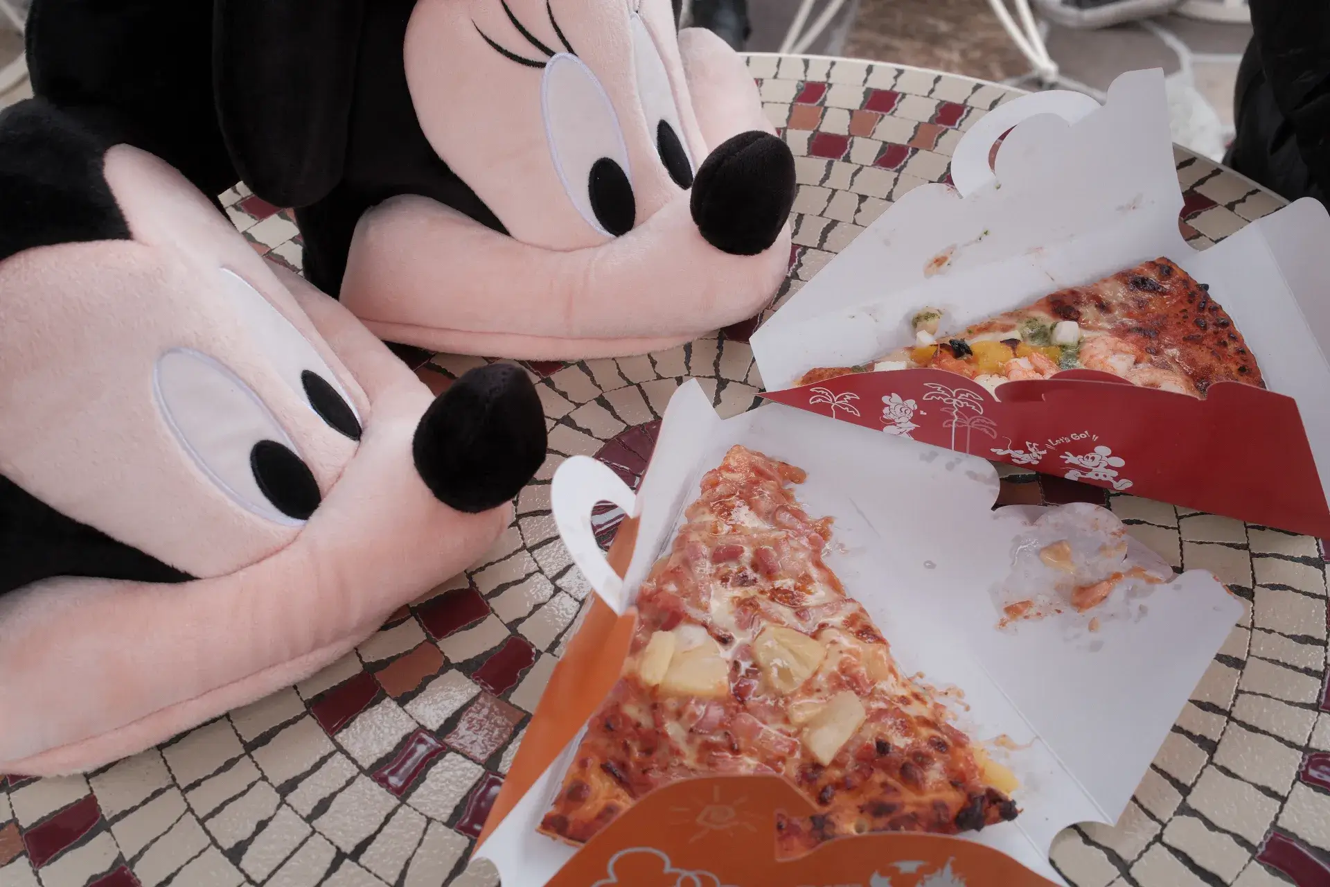 東京ディズニーランドのテーブルでミッキーとミニーのファンキャップと並べられた2枚のカットピザ