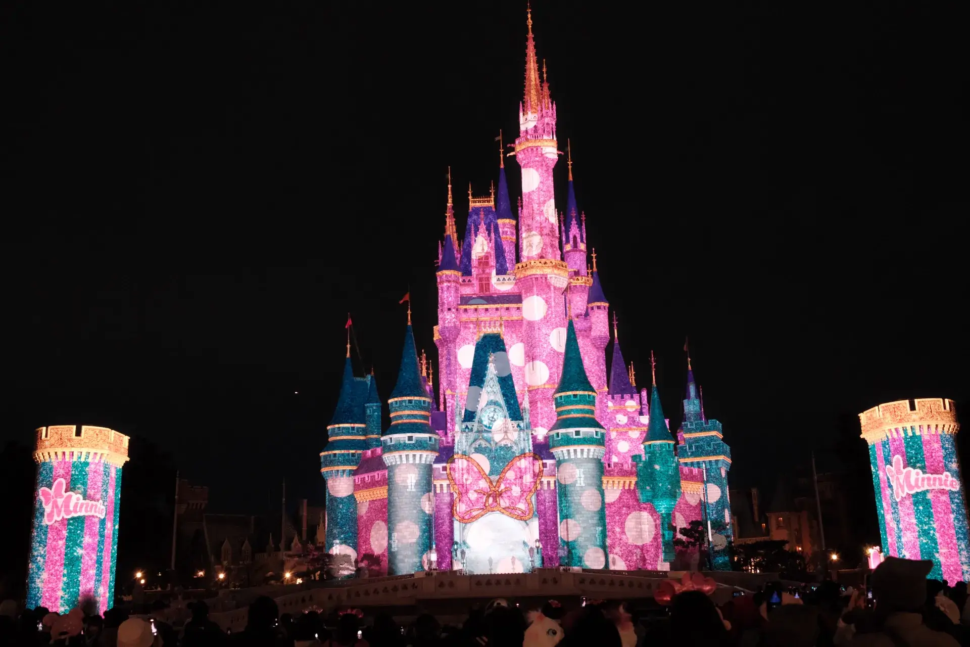 ミニーのファンダーランドの環境演出でピンクのドット柄やリボンの模様が映し出された夜のシンデレラ城